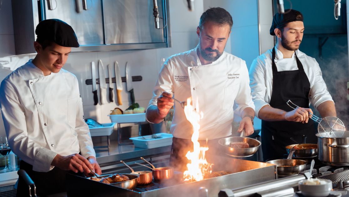 A Group Of Chefs Cooking In A Kitchen
