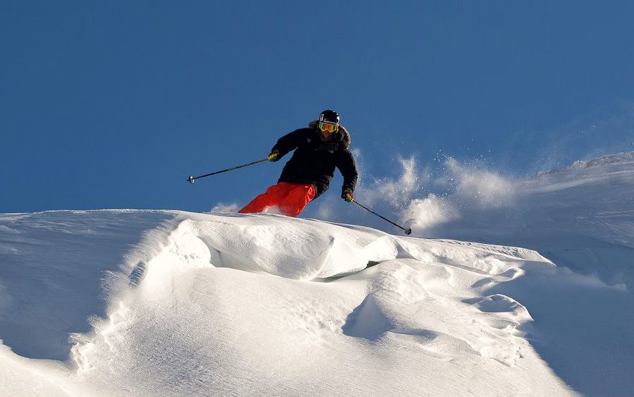 A Person Skiing Down A Snowy Mountain