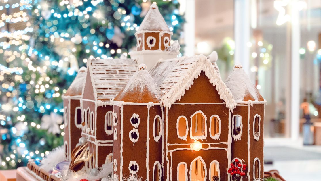 A Gingerbread House In Front Of A Christmas Tree