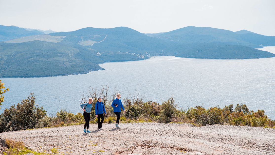 3 people hiking during the day time at a mountain-Chedi Lustica Bay