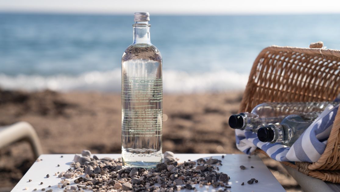 A Bottle Of Water And A Basket On A Beach
