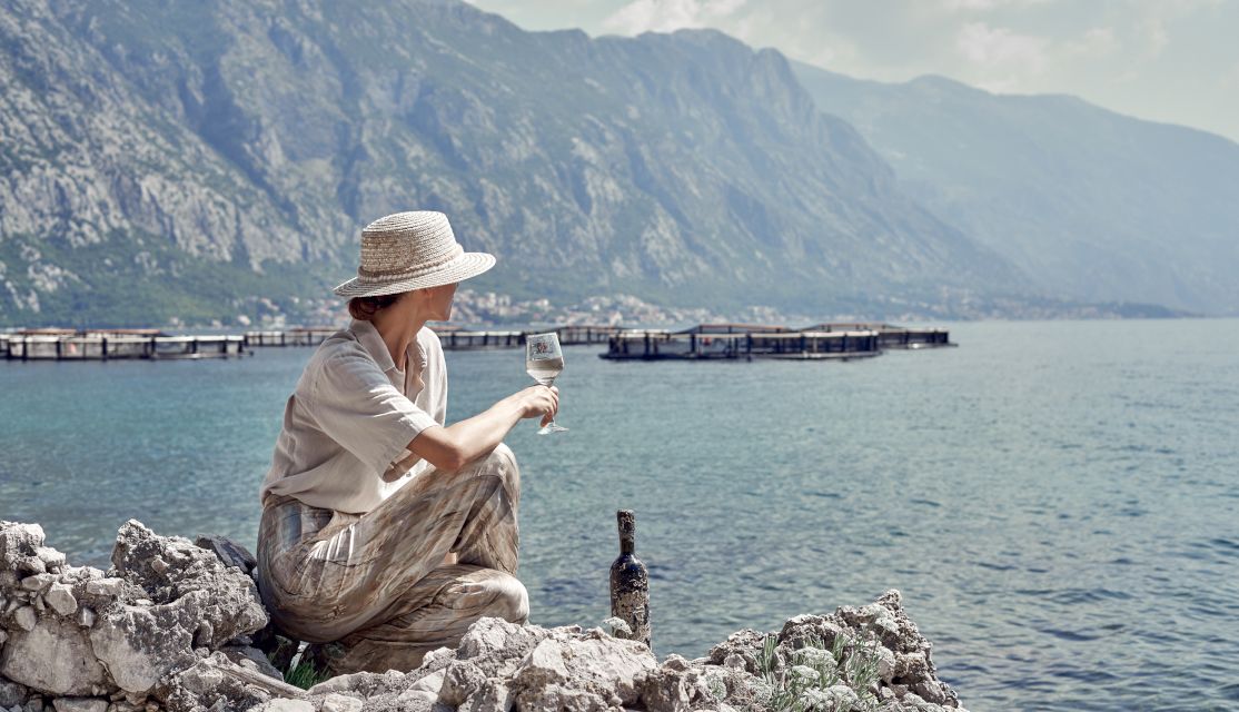 A eoman Sitting On A Rock By The seat With A Bottle Of Wine in montenegro